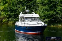 2000 Nimbus 310 Coupe boat cruising on a serene, tree-lined waterway.