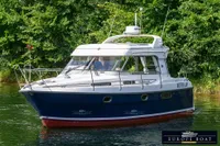 Nimbus 310 Coupe 2000 boat cruising on a serene waterway, surrounded by lush greenery.