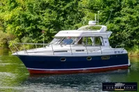 Nimbus 310 Coupe 2000 boat cruising on a serene river with lush greenery.