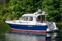 Nimbus 310 Coupe 2000 boat on a serene waterway, surrounded by lush greenery.