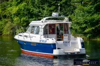Nimbus 310 Coupe 2000 boat cruising on a serene river, surrounded by lush greenery.