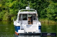 Nimbus 310 Coupe boat from 2000 on a serene waterway, surrounded by lush greenery.