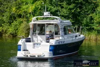 Nimbus 310 Coupe 2000 boat cruising on a serene river with lush greenery.
