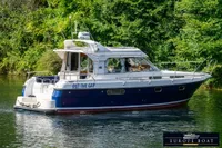 Nimbus 310 Coupe 2000 boat cruising on a serene river, surrounded by lush greenery.