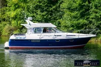 Nimbus 310 Coupe 2000 boat cruising on a serene river with lush green background.