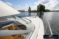 Nimbus 310 Coupe 2000 cruising on a scenic waterway under a partly cloudy sky.