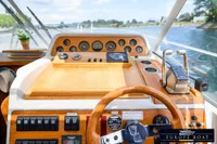 Pilothouse of 2000 Nimbus 310 Coupe with wooden dashboard and steering wheel on a sunny day.