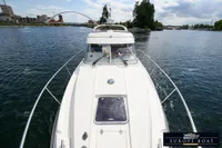 Nimbus 310 Coupe 2000 cruising on a scenic river with cityscape background.