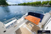 Nimbus 310 Coupe boat deck with seating and table, cruising on a scenic waterway.