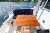 Nimbus 310 Coupe 2000 boat with wooden table and blue seating on deck.