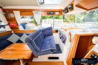 Interior of 2000 Nimbus 310 Coupe with blue seating, wooden accents, and large windows.