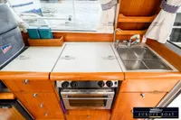 Compact kitchen area in a 2000 Nimbus 310 Coupe boat with sink and stove.