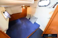 Cozy cabin interior of 2000 Nimbus 310 Coupe with blue bedding and striped pillows.