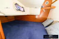Cozy cabin interior of 2000 Nimbus 310 Coupe with striped pillows and wooden accents.