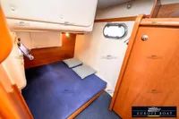 Cozy cabin interior of 2000 Nimbus 310 Coupe with wooden finish and porthole.