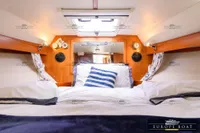 Cozy cabin interior of 2000 Nimbus 310 Coupe with nautical decor and bedding.