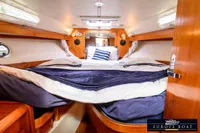 Cozy cabin interior of 2000 Nimbus 310 Coupe with plush bedding and wooden accents.