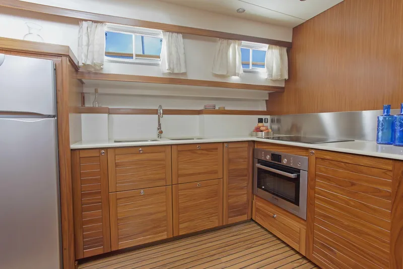  Yacht Photos Pics Modern kitchen interior on 2026 Sasga Yachts 55, featuring wood cabinetry and stainless steel appliances.