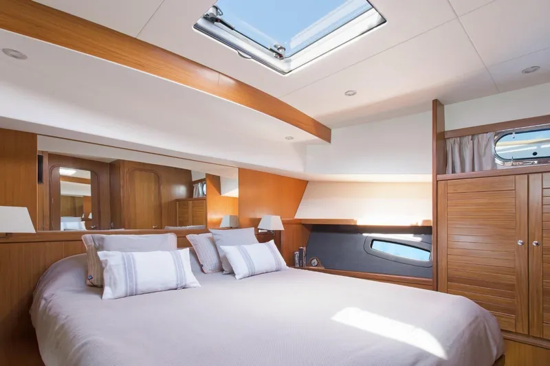  Yacht Photos Pics Luxurious bedroom interior of 2026 Sasga Yachts 55, featuring elegant wood finishes and skylight.