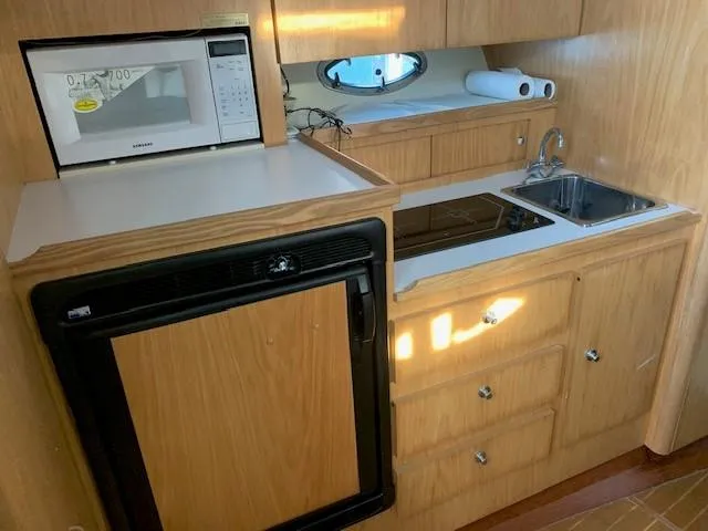 Mickadoo Yacht Photos Pics 2001 Tiara Yachts 3100 interior kitchen with microwave, sink, and wooden cabinetry.
