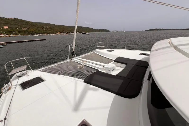 Fregata Lagoon Yacht Photos Pics 2023 Lagoon 46 catamaran deck with seating, overlooking serene waters and distant shoreline.