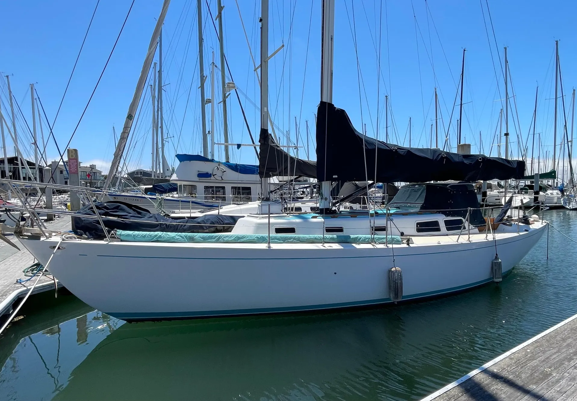 1964 CAL 40 sailboat docked at marina, surrounded by other boats under clear blue sky.