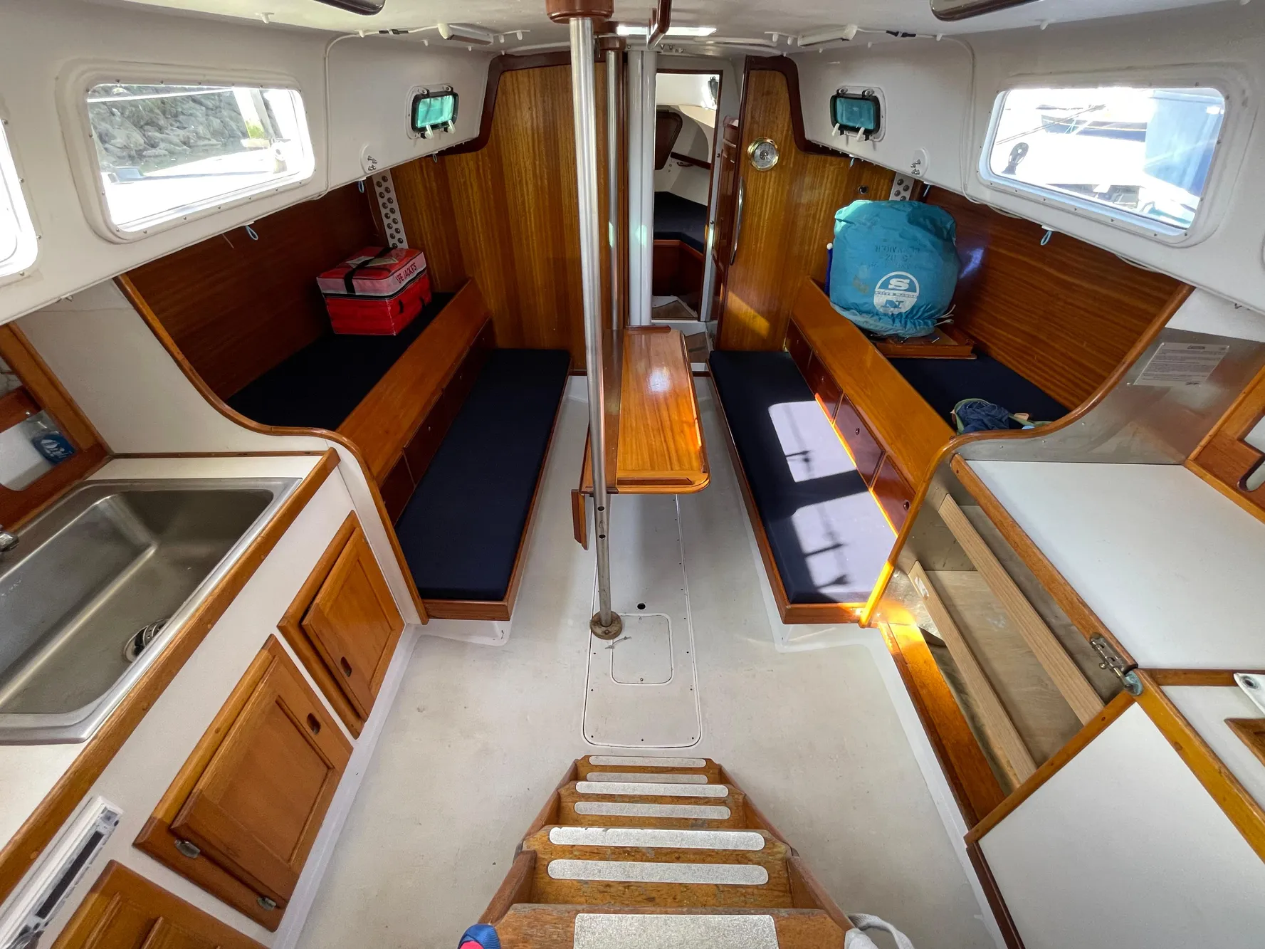 Interior of a 1964 CAL 40 sailboat with wooden cabinetry and seating.