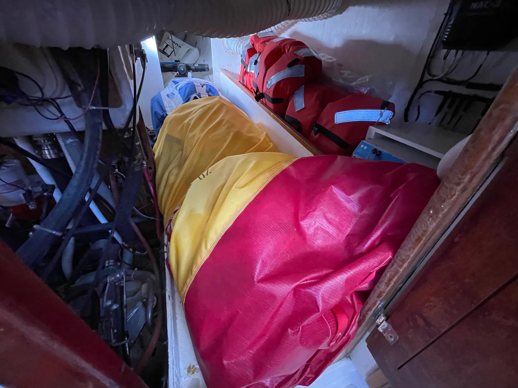 Storage area in a 1964 CAL 40 sailboat with colorful bags and life jackets.