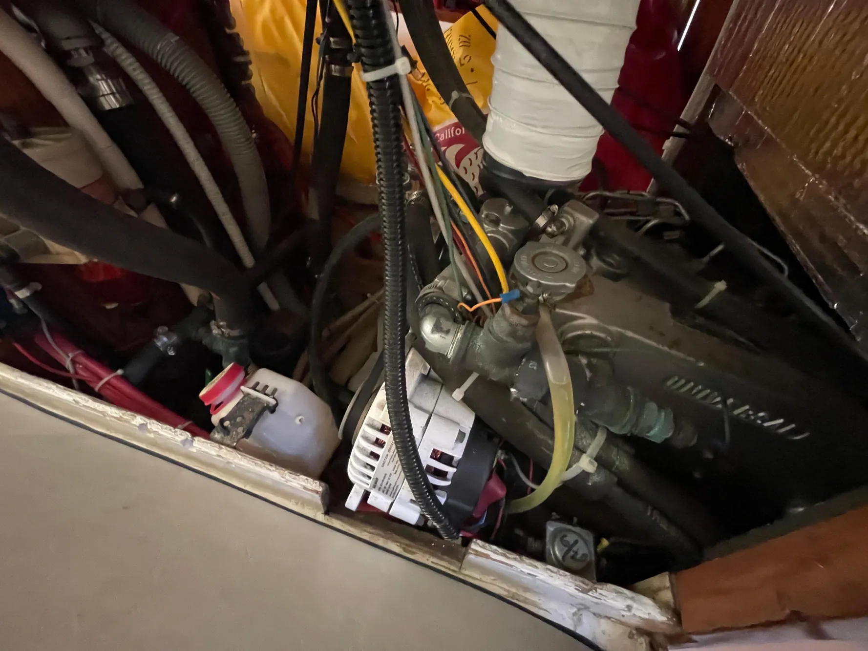 Engine compartment of a 1964 CAL 40 sailboat, showing various hoses and mechanical components.