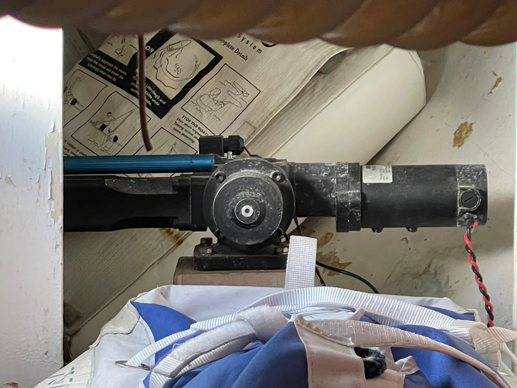 Motor mechanism inside a CAL 40 sailboat from 1964, with instructional diagrams in the background.