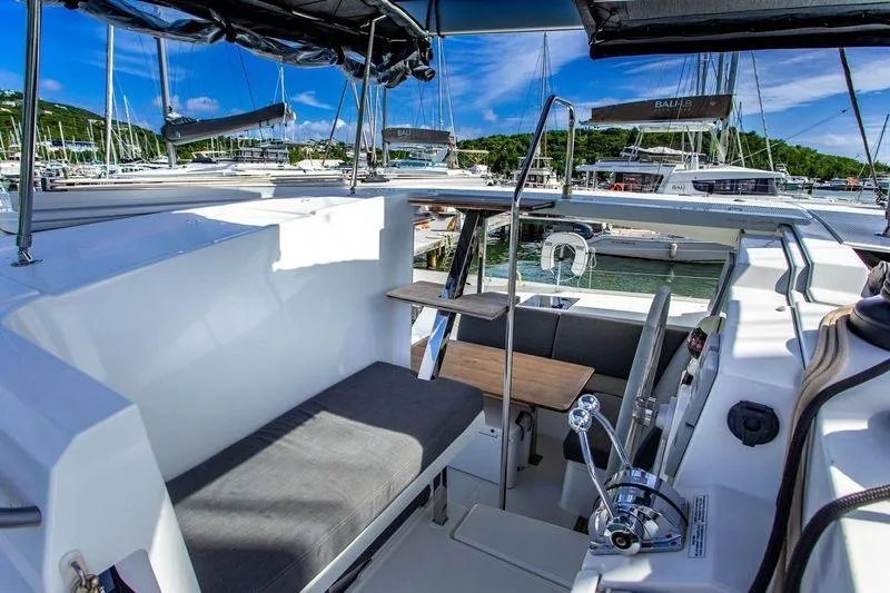 Bodhi Quest Yacht Photos Pics 2023 Fountaine Pajot Isla 40 catamaran cockpit with seating and helm, docked in marina.