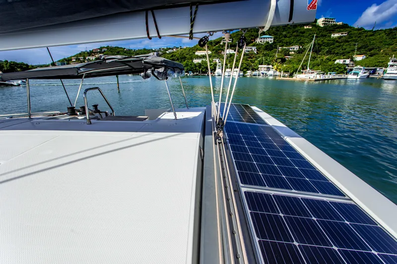 Bodhi Quest Yacht Photos Pics 2023 Fountaine Pajot Isla 40 catamaran with solar panels, docked in a scenic marina.