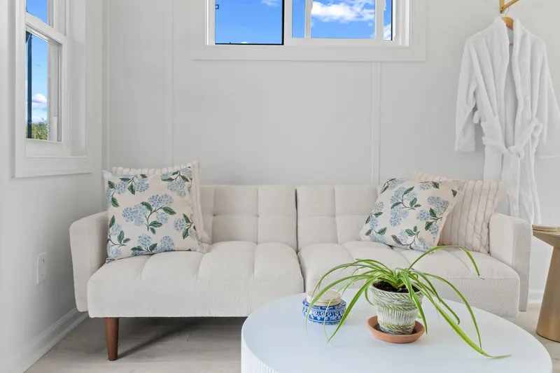  Yacht Photos Pics Cozy interior of 2026 Hanks 26 Houseboat with white sofa, floral pillows, and potted plant.