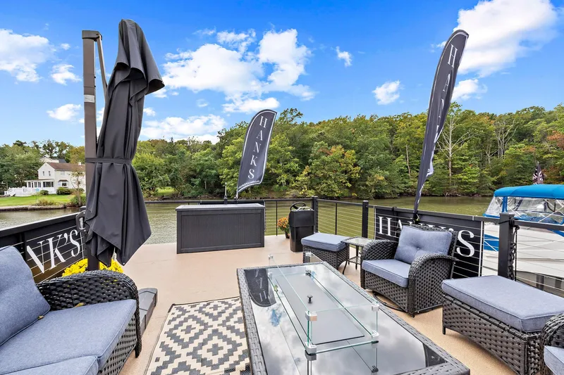  Yacht Photos Pics Luxurious 2026 Hanks 26 Houseboat deck with modern outdoor seating and scenic river view.