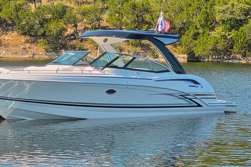  Yacht Photos Pics 2026 Formula 350 Crossover Bowrider I/O on a serene lake, surrounded by lush greenery.