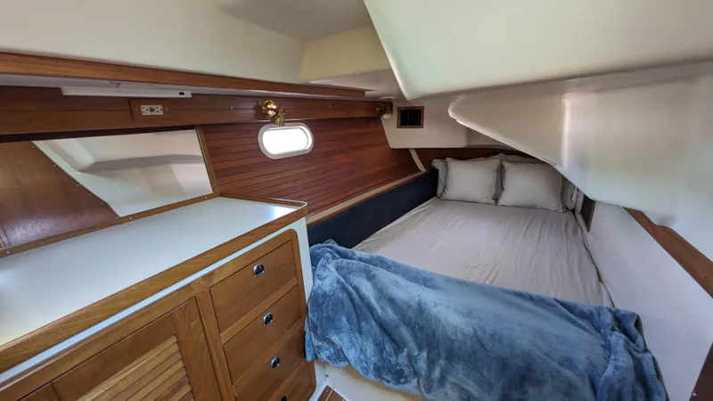  Yacht Photos Pics 2004 Catalina 42 MkII cabin interior with bed, wooden cabinetry, and porthole window.