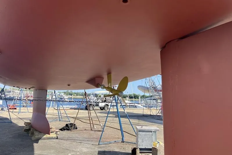 Remedy Yacht Photos Pics Underneath view of a 2012 Jeanneau 57 yacht on dry dock, showcasing the propeller and keel.