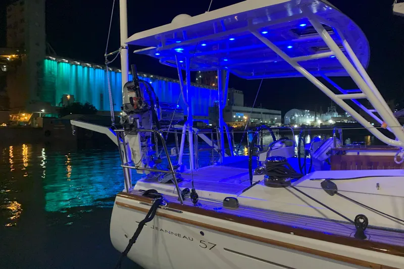 Remedy Yacht Photos Pics Jeanneau 57 sailboat, 2012 model, docked at night with blue lights reflecting on water.