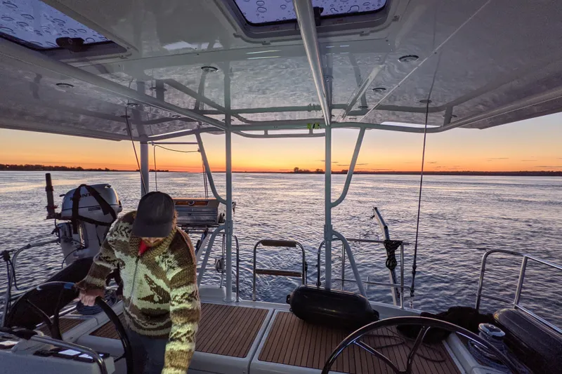 Remedy Yacht Photos Pics Man steering Jeanneau 57 yacht at sunset, 2012 model, on calm waters.