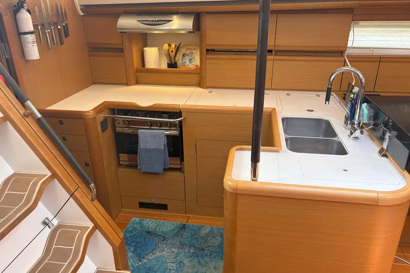 Remedy Yacht Photos Pics Modern kitchen interior of 2012 Jeanneau 57 yacht with wooden cabinetry and stainless steel appliances.