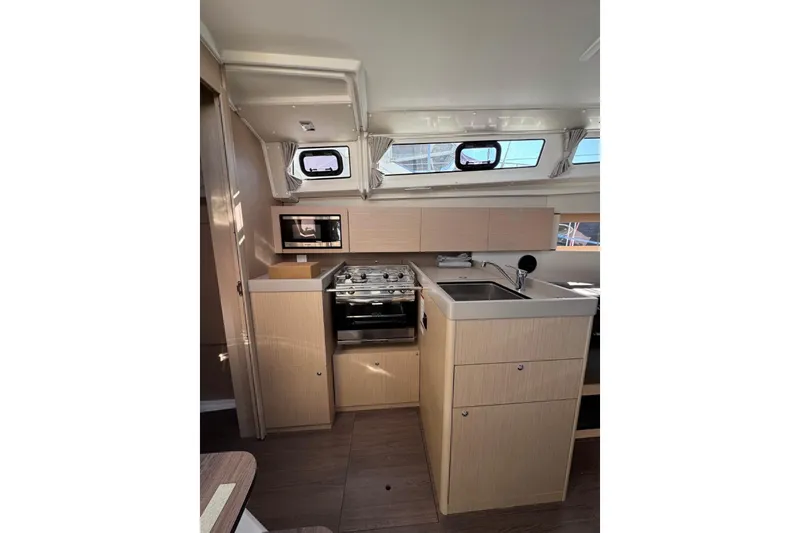 At Last Yacht Photos Pics Modern kitchen interior of 2023 Beneteau Oceanis 38.1 yacht with stove and sink.