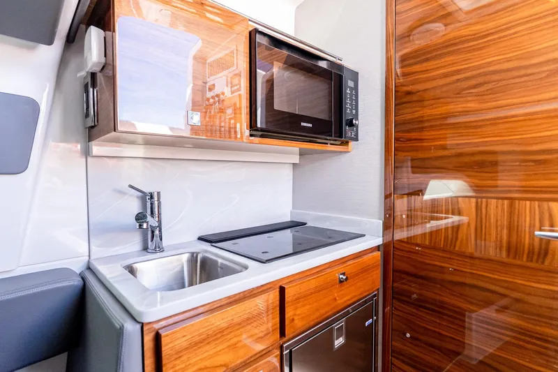  Yacht Photos Pics 2023 Valhalla V-46 boat interior kitchen with sink, microwave, and wooden cabinetry.