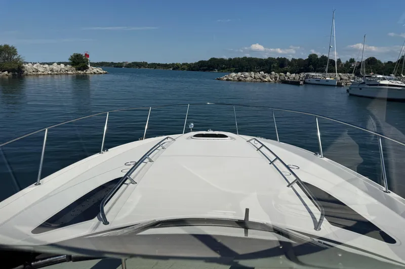  Yacht Photos Pics 2010 Sea Ray 370 Sundancer cruising in a serene marina with sailboats and rocky shoreline.