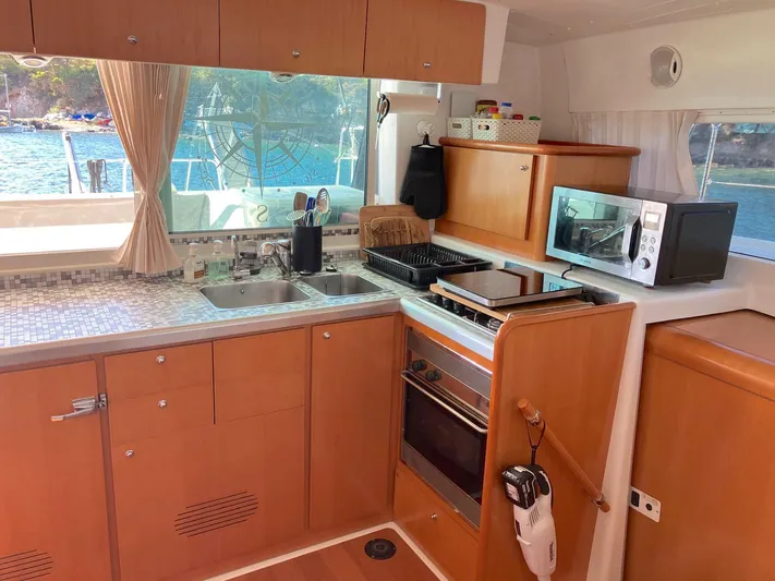 Kirlana Yacht Photos Pics Modern kitchen interior on a 2006 Lagoon 420 yacht, featuring appliances and scenic window view.