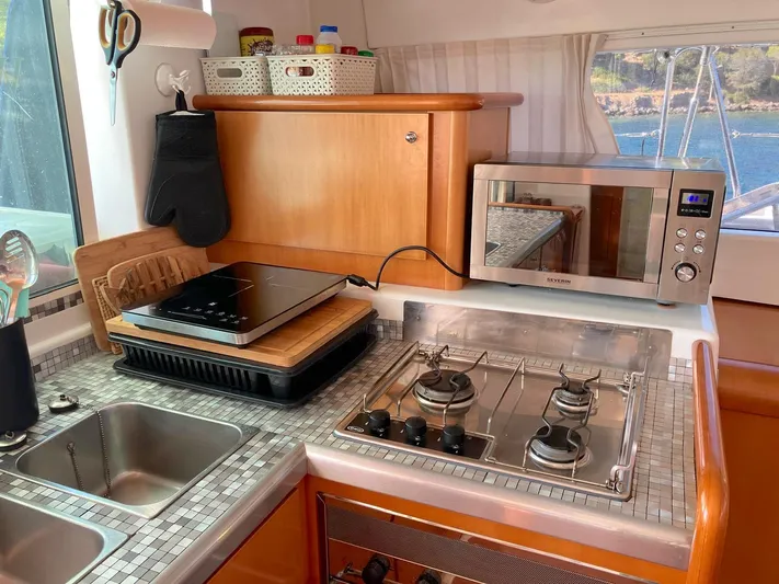 Kirlana Yacht Photos Pics Compact kitchen in a 2006 Lagoon 420 yacht with stove, microwave, and sink.