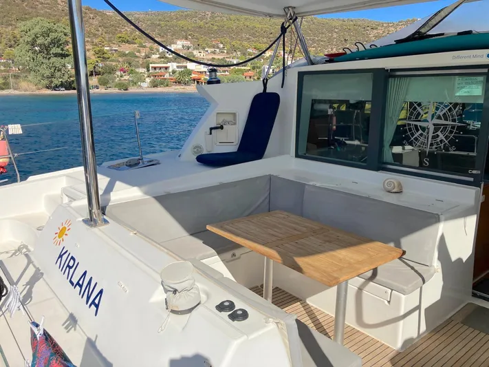 Kirlana Yacht Photos Pics Lagoon 420 catamaran deck with seating area, table, and scenic coastal view.