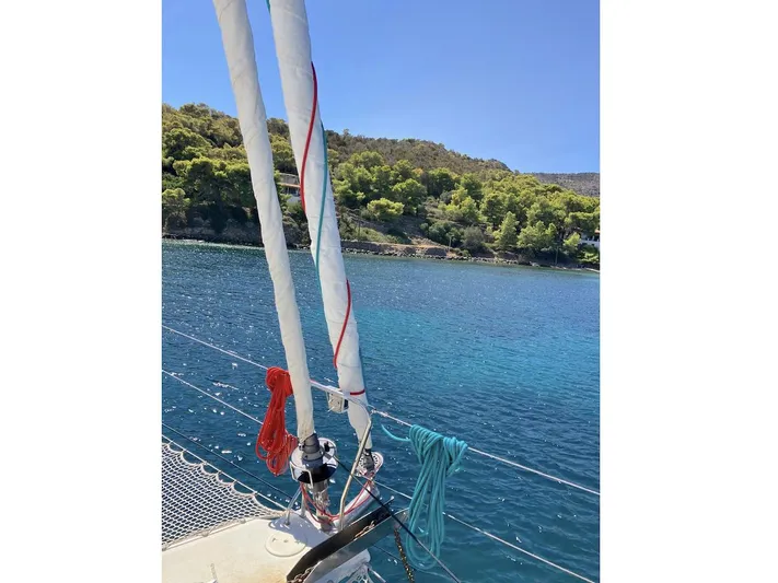 Kirlana Yacht Photos Pics Sailboat Lagoon 420, 2006 model, anchored in clear blue water near a lush green shoreline.