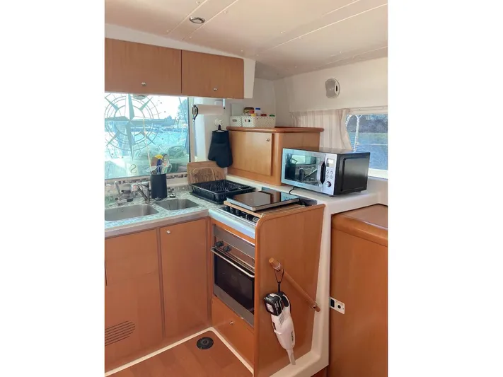 Kirlana Yacht Photos Pics Compact kitchen in a 2006 Lagoon 420 catamaran with modern appliances and wooden cabinetry.
