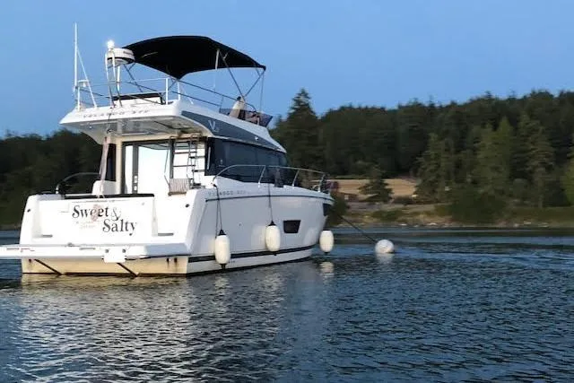  Yacht Photos Pics 2018 Jeanneau Velasco 37F yacht on calm water, surrounded by trees.