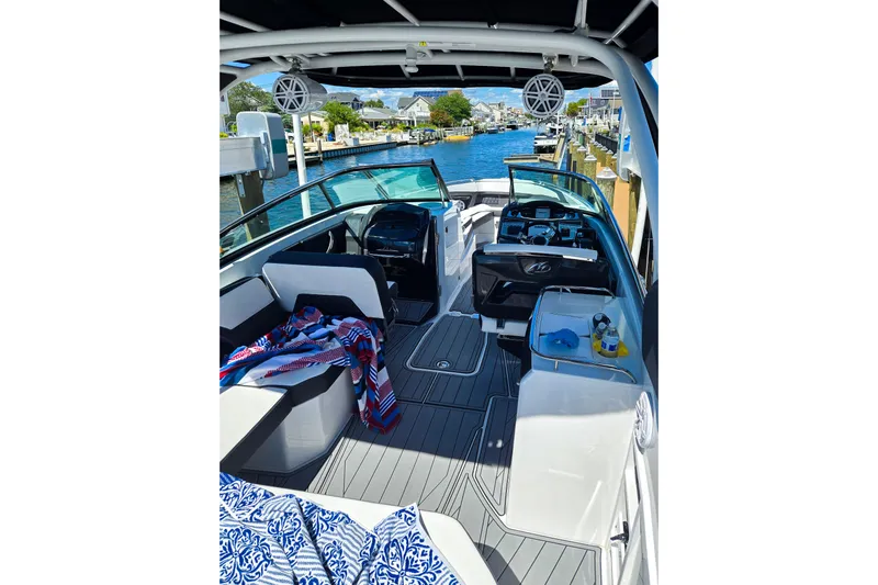  Yacht Photos Pics 2024 Monterey 305SS Super Sport boat interior with seating and dashboard, docked by a canal.